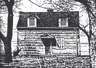 Black and white image of a log cabin. 