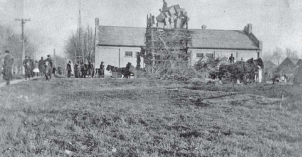 People gather by a large pile of twigs for the Burning the Kaiser event.