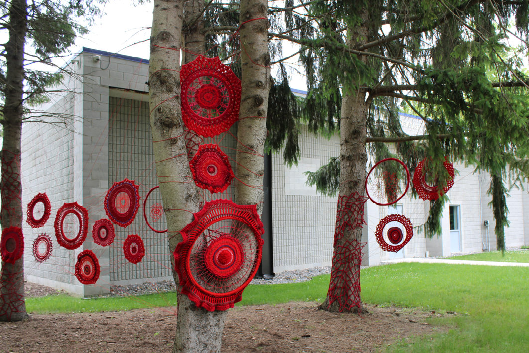 A close up of Tracey-Mae Chambers yarn art installation in the trees at Lambton Heritage Museum