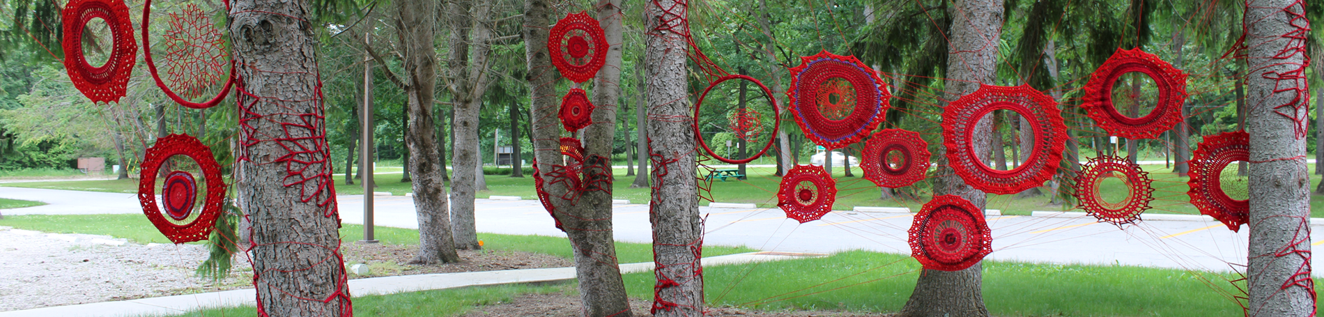 Yarn art installation by Tracey-Mae Chambers in trees at Lambton Heritage Museum