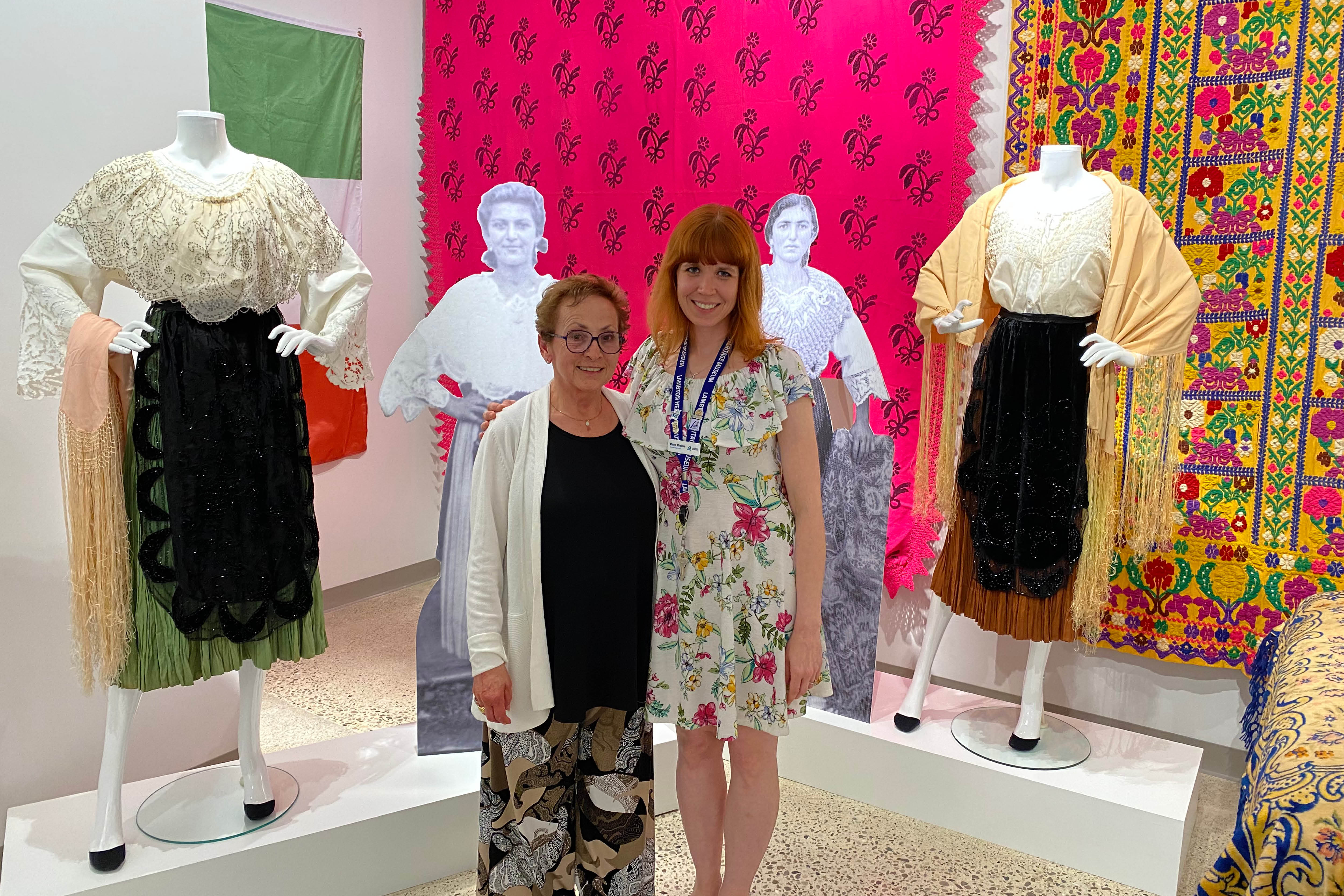 LHM Curator/Supervisor Dana Thorne and exhibit contributor Antonia Ambrose stand next to Italian dresses.