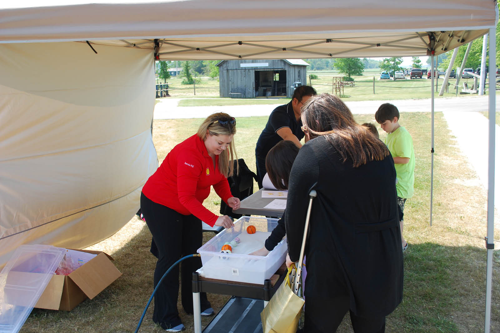 Shell experts operate a fluidized bed demonstration in a plastic tub outside under a tent at the Oil Museum's Shell PA Day in 2023.