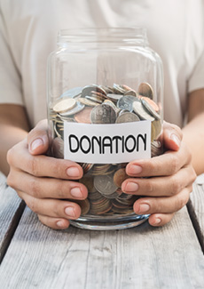 Hands holding a jar with words "donation" on it.