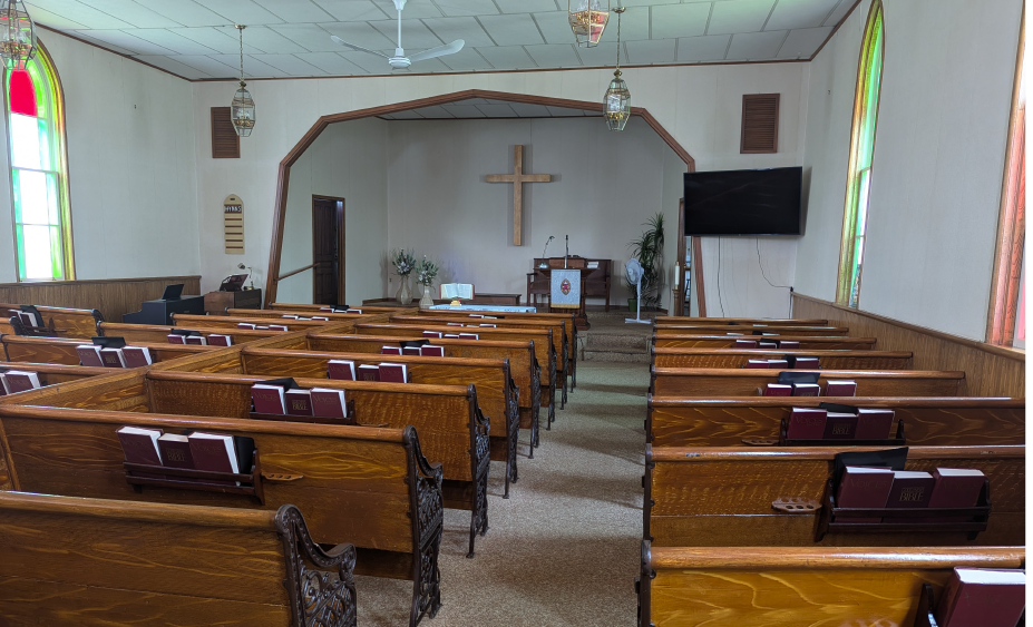 Brown pews and an alter with stained glass windows