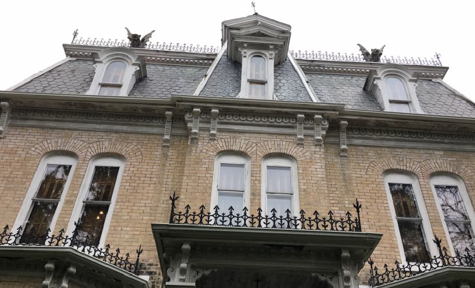 Yellow brick house with gargoyles and ornate details.